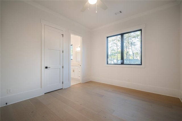 unfurnished bedroom featuring light wood-type flooring, ensuite bathroom, ceiling fan, and ornamental molding