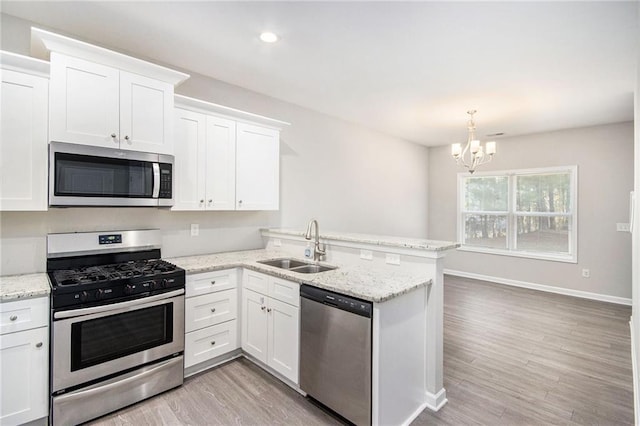 kitchen with stainless steel appliances, white cabinets, a chandelier, and sink