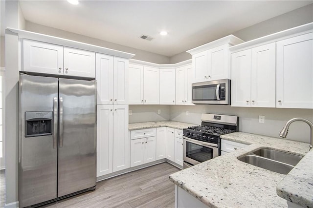 kitchen featuring light stone counters, stainless steel appliances, white cabinetry, and sink