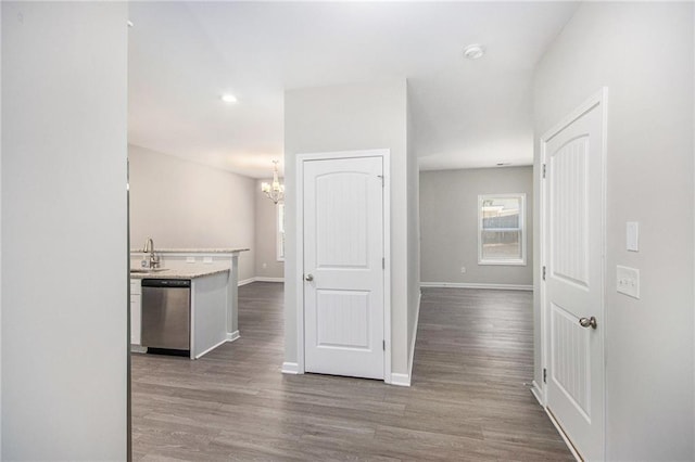 corridor featuring sink, a notable chandelier, and hardwood / wood-style floors