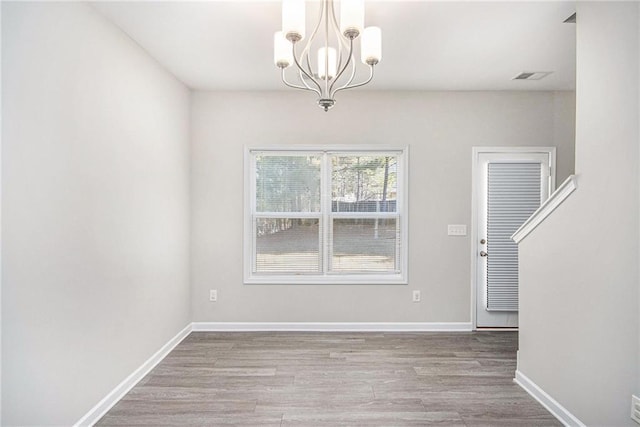 unfurnished dining area with a notable chandelier and light hardwood / wood-style flooring