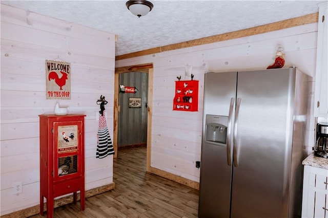 4625 Ben Hill Dr, Oakwood, GA 30566 - kitchen with stainless steel fridge, wood walls, light wood-style floors, baseboards, and white cabinetry