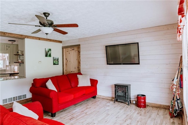 4625 Ben Hill Dr, Oakwood, GA 30566 - living area featuring a wood stove, a ceiling fan, wood finished floors, and wood walls