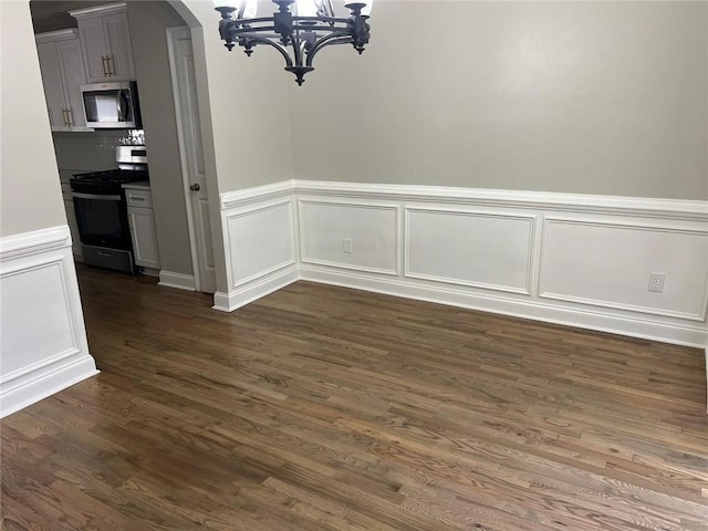 unfurnished dining area with dark hardwood / wood-style floors and an inviting chandelier