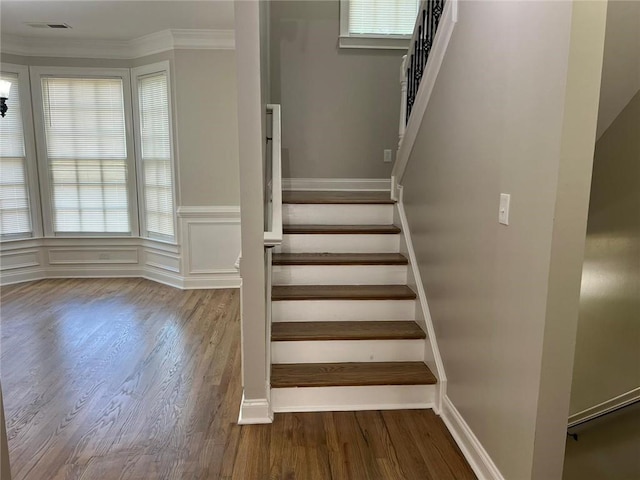 stairs with hardwood / wood-style flooring, a healthy amount of sunlight, and ornamental molding