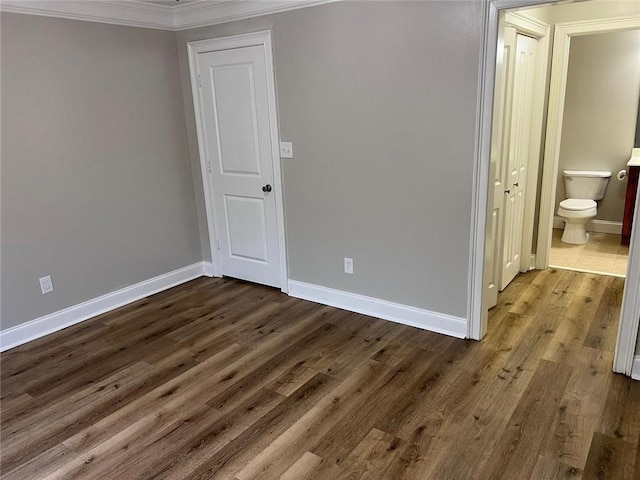 unfurnished bedroom with ensuite bathroom, crown molding, and hardwood / wood-style flooring