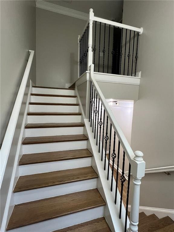 stairway with wood-type flooring and crown molding