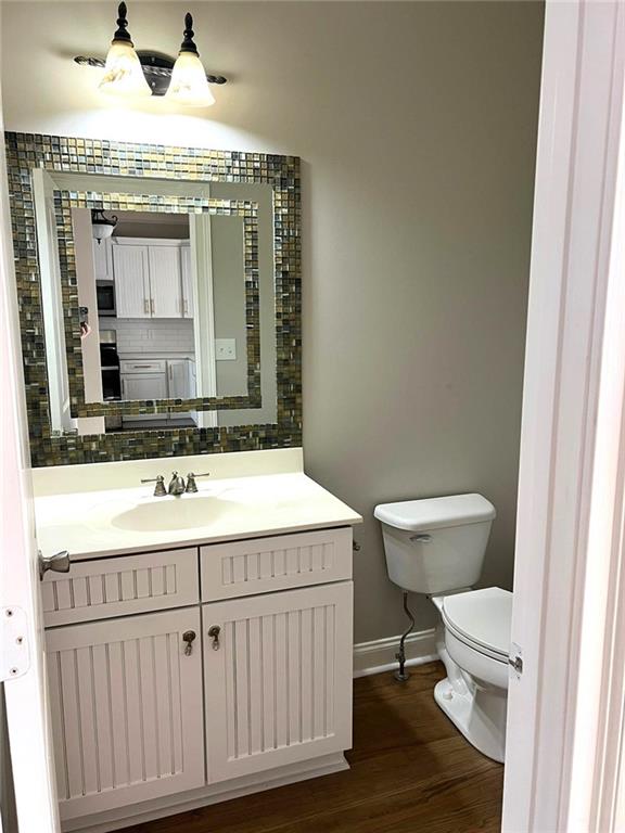 bathroom with hardwood / wood-style floors, vanity, and toilet