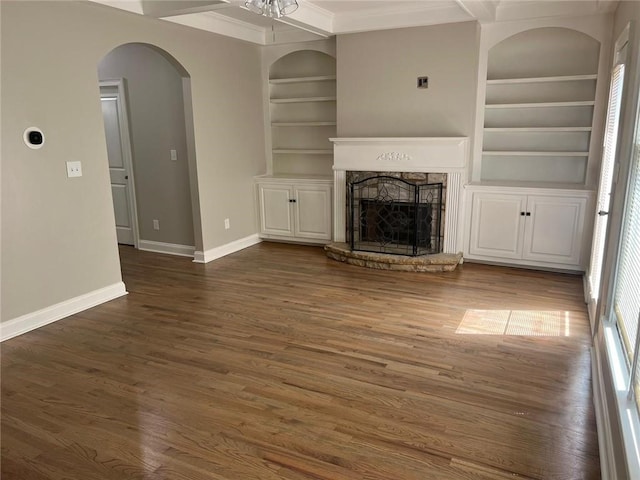 unfurnished living room featuring beam ceiling, dark hardwood / wood-style flooring, built in features, and a fireplace