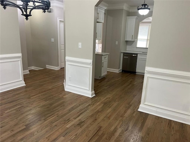 kitchen with white cabinetry, dark wood-type flooring, tasteful backsplash, stainless steel dishwasher, and ornamental molding