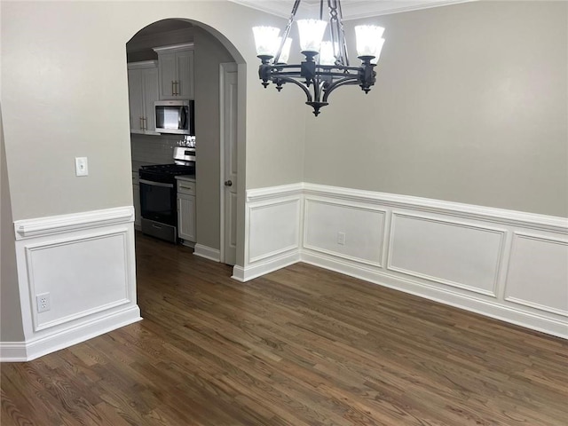 unfurnished dining area featuring crown molding, dark hardwood / wood-style flooring, and a chandelier