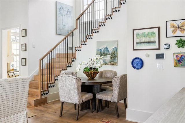 dining room featuring baseboards, wood finished floors, and stairs