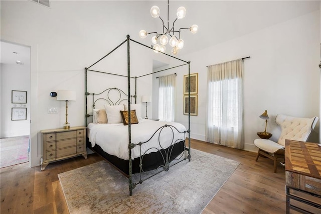 bedroom with wood finished floors, baseboards, and a chandelier