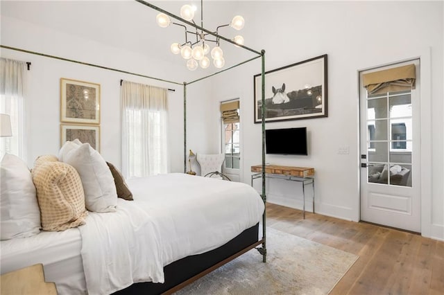 bedroom featuring a chandelier, baseboards, and wood finished floors