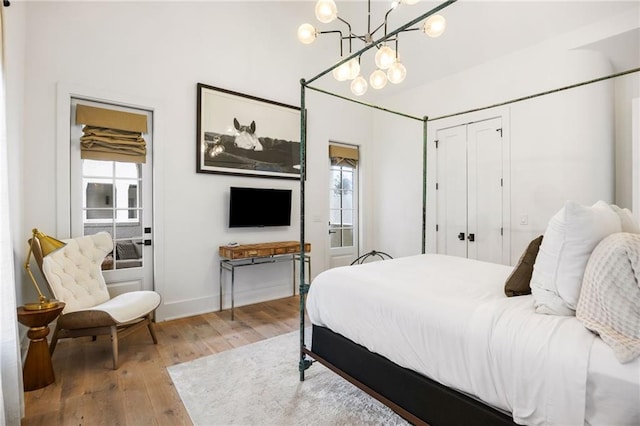 bedroom with a closet, multiple windows, baseboards, and wood finished floors