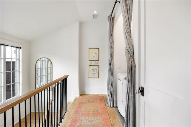 hallway with washing machine and dryer, light wood-style flooring, and baseboards