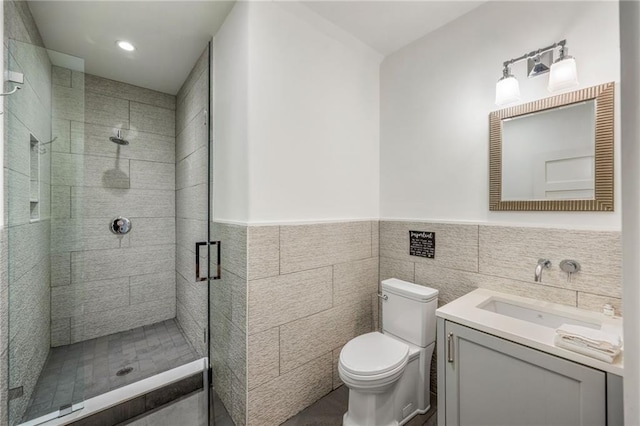 bathroom featuring vanity, a stall shower, wainscoting, tile walls, and toilet