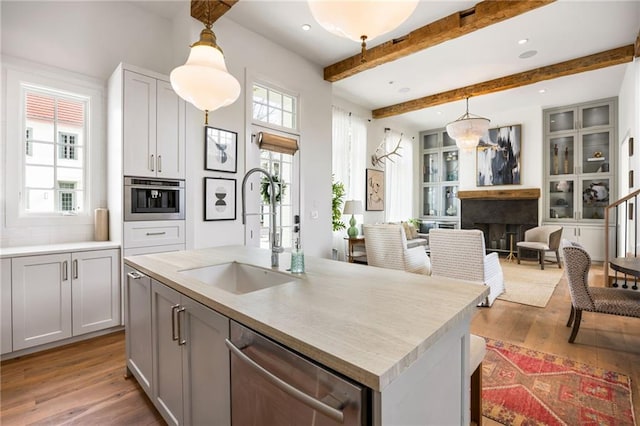 kitchen with light wood finished floors, plenty of natural light, stainless steel appliances, and a sink