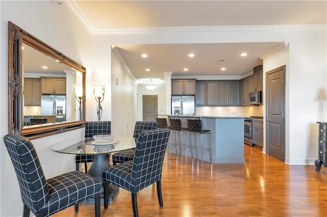 dining area with light hardwood / wood-style flooring and ornamental molding