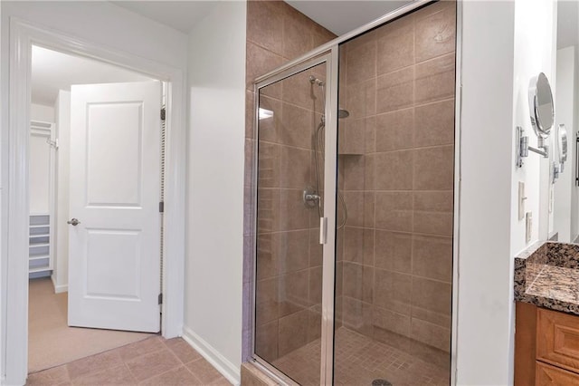 bathroom with a shower with shower door, vanity, and tile patterned flooring