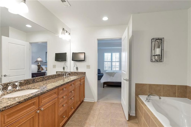 bathroom featuring tiled bath, vanity, and tile patterned flooring