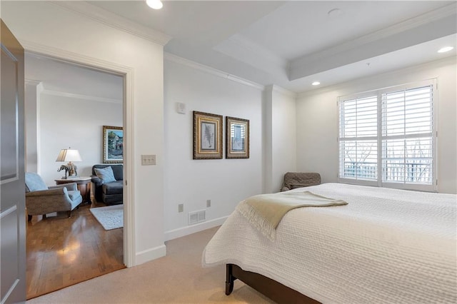 carpeted bedroom with a tray ceiling and crown molding