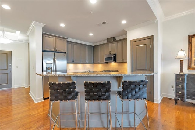 kitchen with light stone counters, a kitchen breakfast bar, a kitchen island with sink, and stainless steel appliances