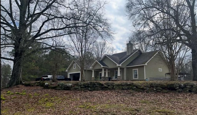 view of front facade with a porch, a chimney, a garage, and board and batten siding