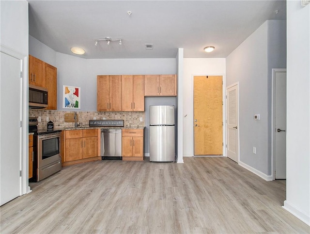 kitchen with light hardwood / wood-style floors, sink, stainless steel appliances, and backsplash