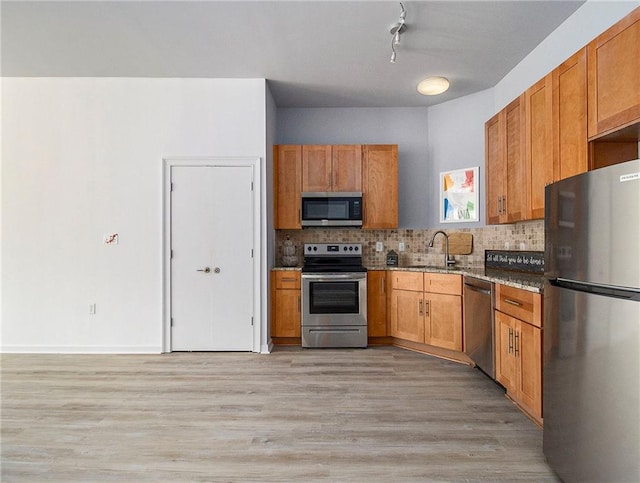 kitchen with rail lighting, light hardwood / wood-style floors, sink, backsplash, and appliances with stainless steel finishes