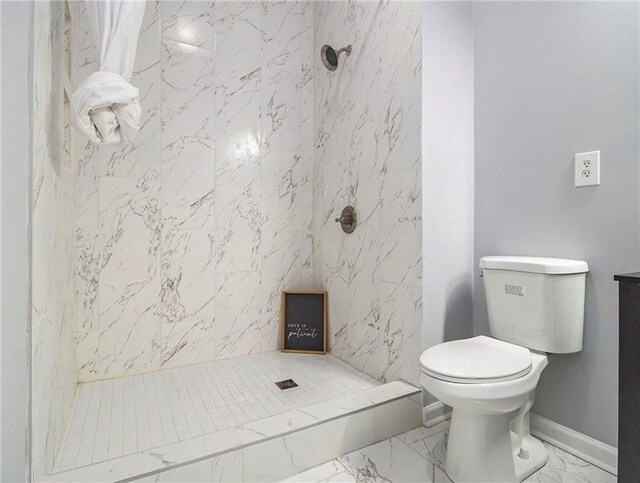 bathroom with a tile shower and toilet