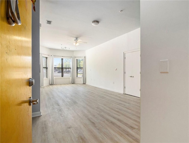 empty room with ceiling fan and light hardwood / wood-style flooring