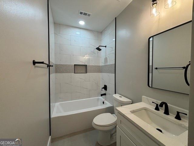 full bathroom with vanity, tiled shower / bath combo, and toilet