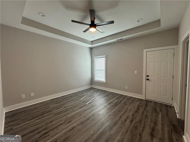 spare room with a tray ceiling, dark hardwood / wood-style floors, and ceiling fan