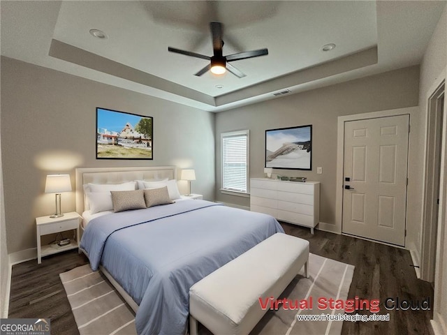 bedroom with a raised ceiling, ceiling fan, and dark hardwood / wood-style flooring