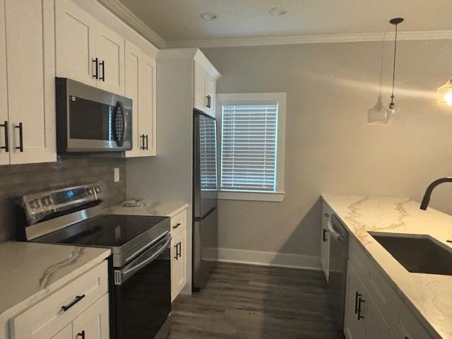 kitchen featuring kitchen peninsula, appliances with stainless steel finishes, sink, pendant lighting, and white cabinetry