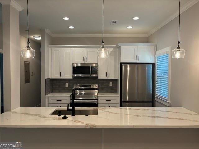 kitchen with light stone countertops, white cabinetry, hanging light fixtures, stainless steel appliances, and a kitchen island with sink