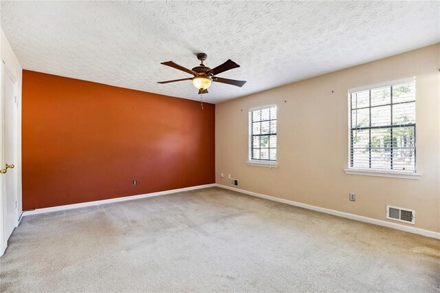 carpeted empty room featuring a textured ceiling and ceiling fan