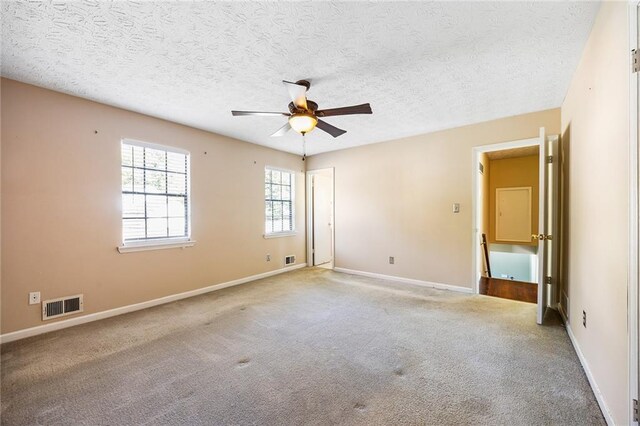 empty room featuring a textured ceiling, carpet, and ceiling fan