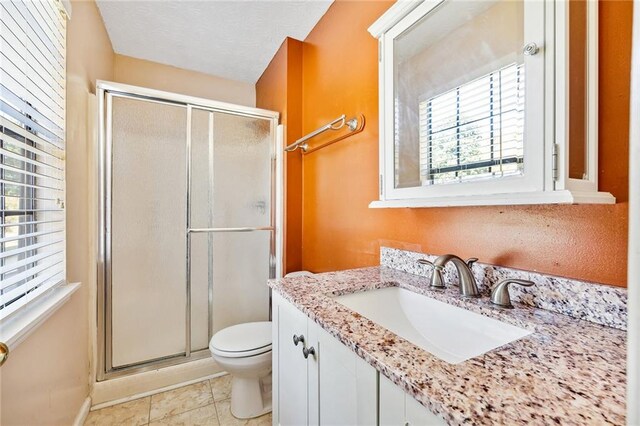 bathroom featuring a shower with door, vanity, toilet, and tile patterned flooring