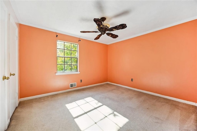 empty room featuring crown molding, light colored carpet, and ceiling fan