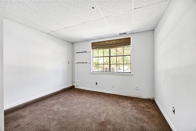 carpeted spare room featuring a drop ceiling