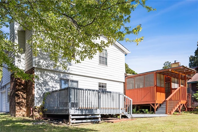 rear view of house featuring a deck, a lawn, and a sunroom