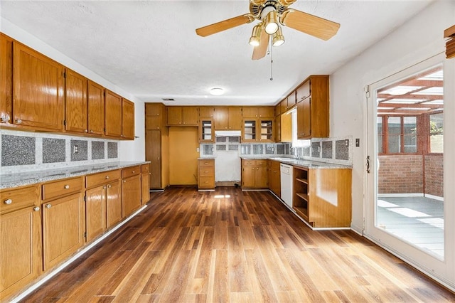 kitchen with decorative backsplash, ceiling fan, light stone countertops, dishwasher, and dark wood-type flooring