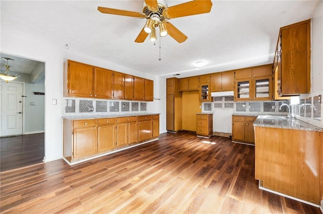 kitchen with decorative backsplash, light stone counters, ceiling fan, dark hardwood / wood-style floors, and sink