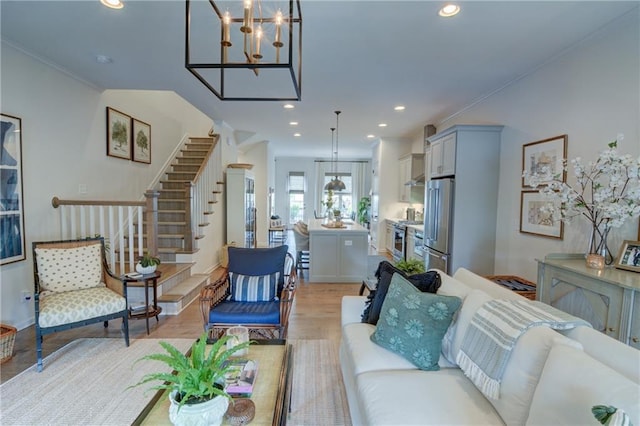 living room featuring a chandelier, stairs, recessed lighting, and light wood-style floors
