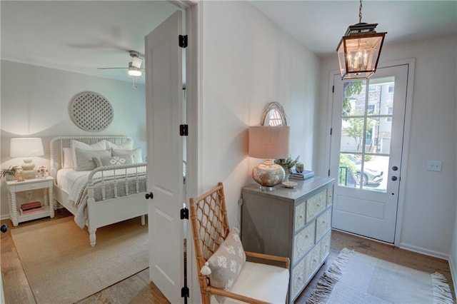 entryway featuring wood finished floors, a chandelier, and a ceiling fan