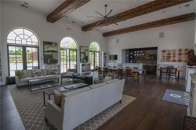 living room featuring beamed ceiling, dark wood finished floors, a high ceiling, and ceiling fan