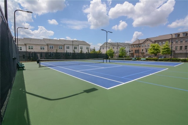 view of tennis court with fence, a residential view, and community basketball court