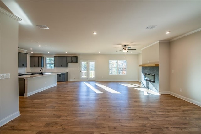 unfurnished living room with a premium fireplace, crown molding, ceiling fan, and dark hardwood / wood-style flooring